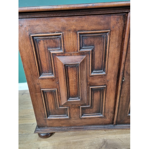 565 - An oak Cupboard fitted pair of geometric moulded cushion doors raised on bun feet by John Nethercott... 