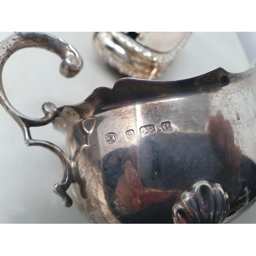 71 - An Edward VII silver Sauce Boat with leafage scroll handle on three hoof feet, Birmingham 1904, and ... 