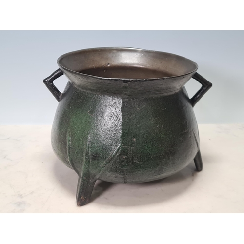 784 - A 17th Century bronze Cauldron with flared rim, angular lugged handles, raised on ribbed tripod supp... 