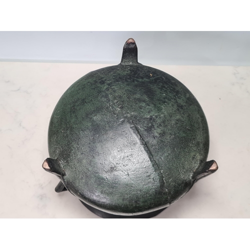 784 - A 17th Century bronze Cauldron with flared rim, angular lugged handles, raised on ribbed tripod supp... 