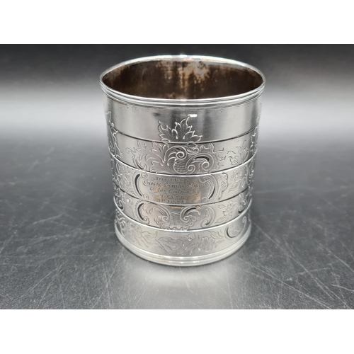 87 - A Victorian silver Mug with floral and scroll engraving, presentation inscription, cross-over handle... 