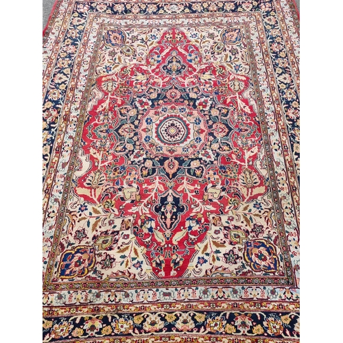 934 - A large bordered Persian Carpet with medallion and corner design on a red and cream ground, the main... 