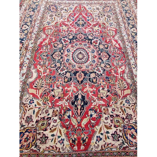 934 - A large bordered Persian Carpet with medallion and corner design on a red and cream ground, the main... 