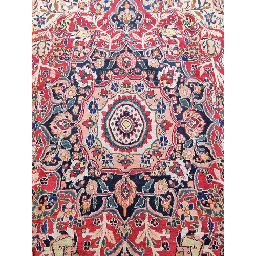 934 - A large bordered Persian Carpet with medallion and corner design on a red and cream ground, the main... 