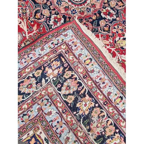 934 - A large bordered Persian Carpet with medallion and corner design on a red and cream ground, the main... 