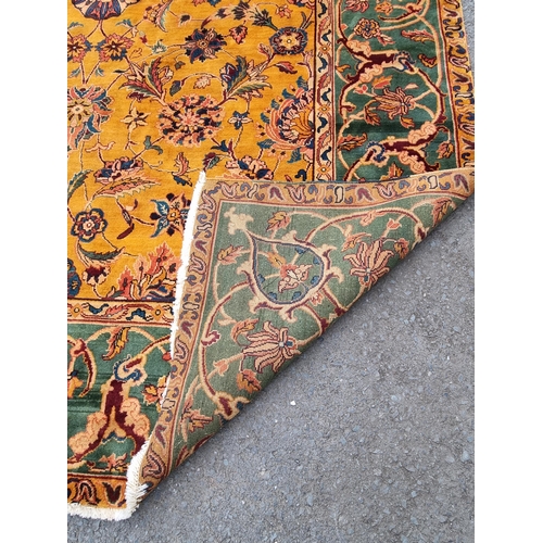 935 - A modern woolen Persian style Rug with trailing floral design on mustard ground within wide green bo... 