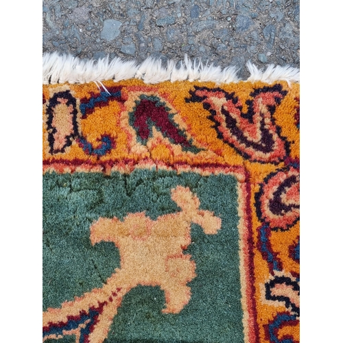 935 - A modern woolen Persian style Rug with trailing floral design on mustard ground within wide green bo... 