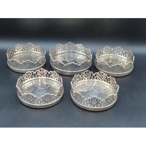 96 - A Set of four Victorian silver Wine Coasters and another, larger en suite, circular the shaped sides... 