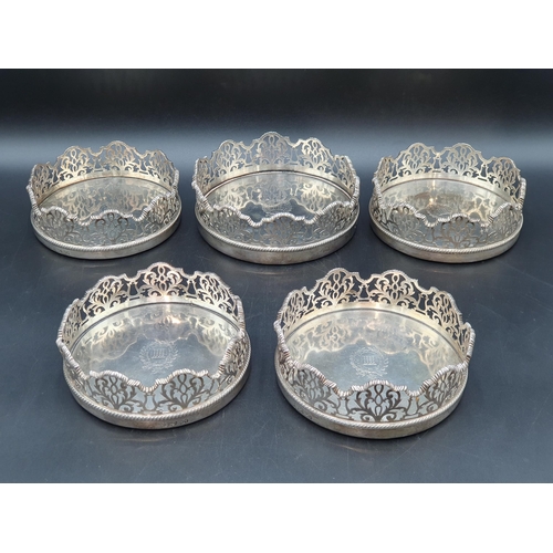 96 - A Set of four Victorian silver Wine Coasters and another, larger en suite, circular the shaped sides... 