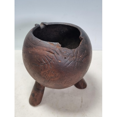 974 - A Tribal hardwood Vessel/Jug with spout, carved line designs and raised on tapered tripod supports, ... 