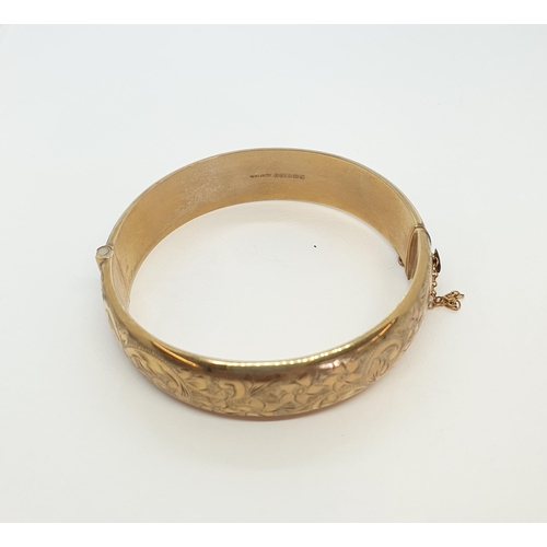 203 - A 9ct gold hinged Bangle the front with scroll engraving, approx 22.50gms