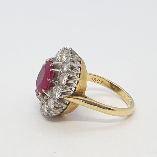 213 - A Ruby and Diamond Cluster Ring claw-set oval mixed-cut ruby surrounded by a frame of twelve pavé-se... 