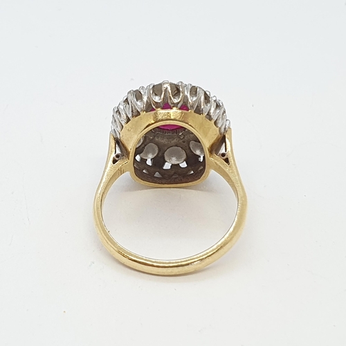 213 - A Ruby and Diamond Cluster Ring claw-set oval mixed-cut ruby surrounded by a frame of twelve pavé-se... 