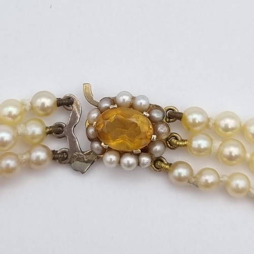 206 - A triple row of graduated Cultured Pearls on clasp set oval-cut citrine within frame of half pearls