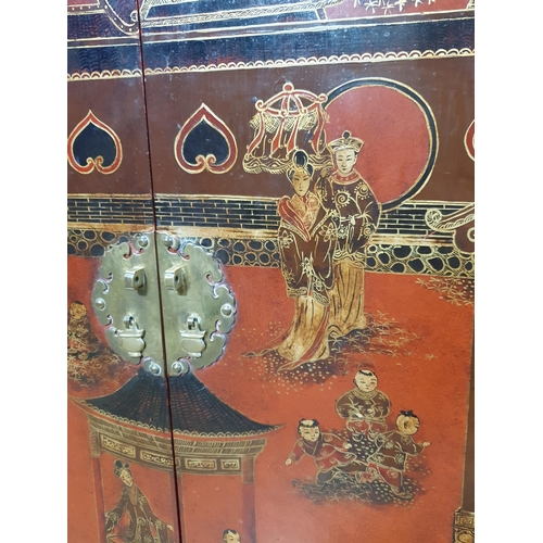 629 - A Chinese red lacquered Cupboard with double-hinged top above a pair of cupboard doors decorated fig... 