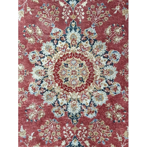 941 - A fine Persian style wool Rug with floral borders and central stylised flower head on a red ground, ... 