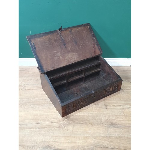 528 - An antique oak Table Desk with sloping hinged top and carved flowerheads to the frieze