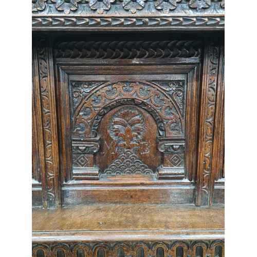 529 - An 17th Century oak Deuddarn, the upper frieze carved with flowerheads above two carved panel doors ... 