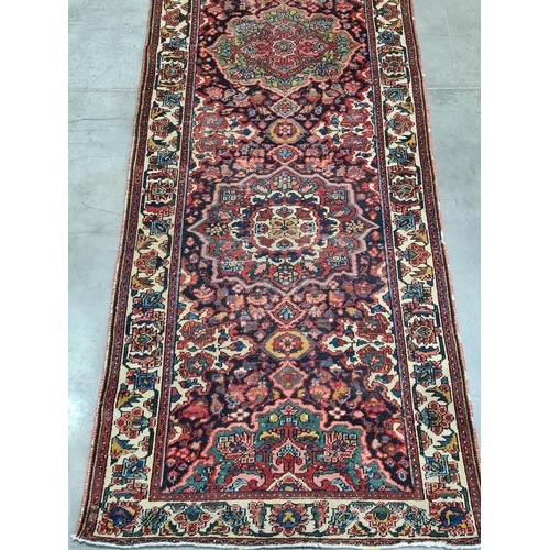 932 - A bordered Persian Runner with geometric floral field in red, blue, cream, etc within tramline borde... 