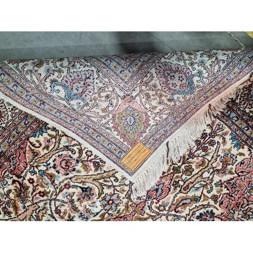 930 - A Kashmir Rug, with floral and scrolled border and floral scrolled designs to the central cream grou... 