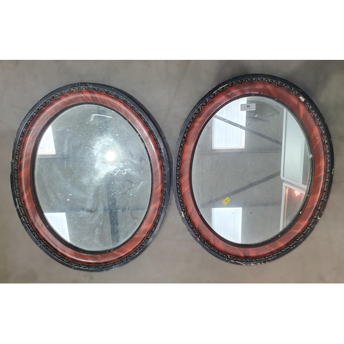 50 - A pair of oval Wall Mirrors in simulated rosewood and ebonised frames, 62 x 51 cms