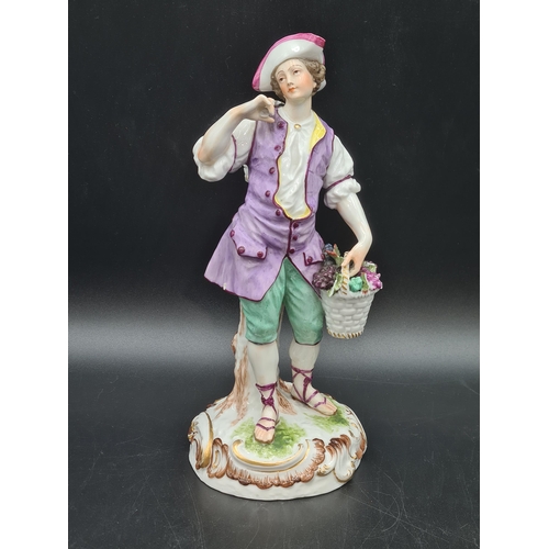 51 - A Meissen Figure of a Youth carrying panniers of grapes, painted costume, on scroll moulded circular... 