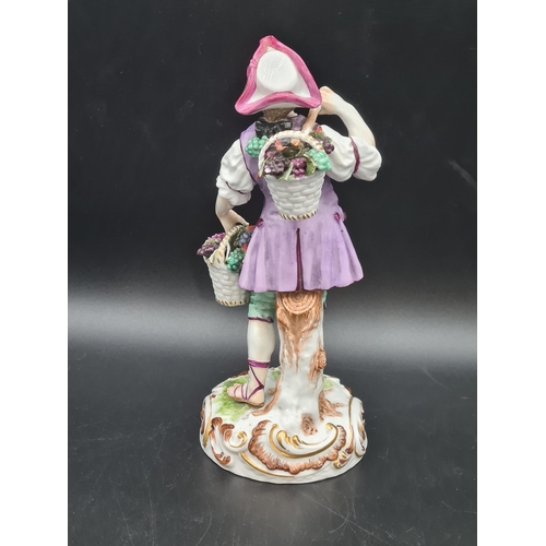 51 - A Meissen Figure of a Youth carrying panniers of grapes, painted costume, on scroll moulded circular... 