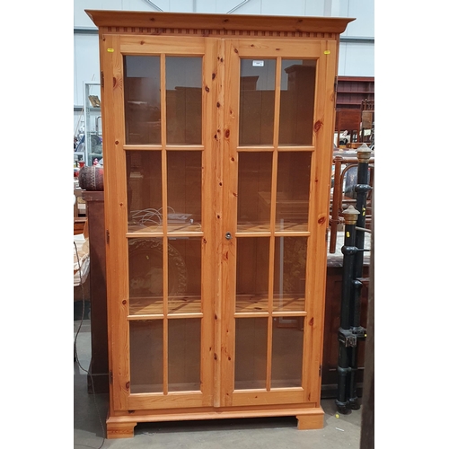 648 - A modern pine Bookcase/Display Cabinet with pair of glazed doors, with three interior shelves raised... 