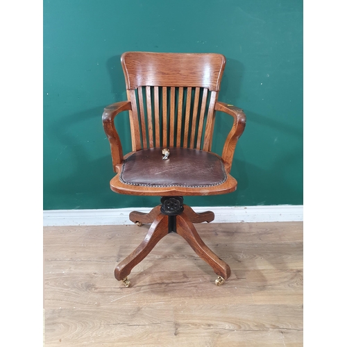 675 - An oak framed Swivel Chair with leather style upholstered seat, raised on quadruple supports and cas... 