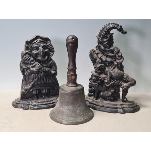 28 - A pair of cast iron Punch and Judy Doorstops and a Hand Bell with turned wooden handle, handle A/F. ... 