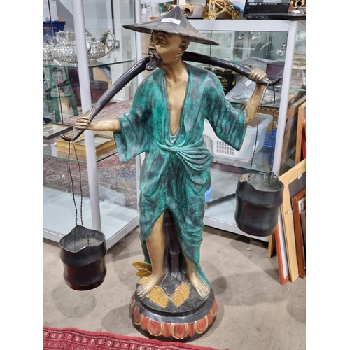 758 - A bronze effect brass and painted Figure of a man carrying two water buckets with a yolk,  3ft 5in H... 