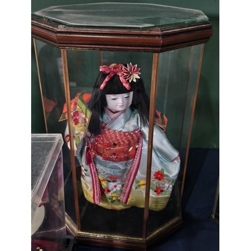 270 - Two Japanese Dolls in octagonal glazed cases, another Japanese Doll in a case, a pottery Japanese st... 