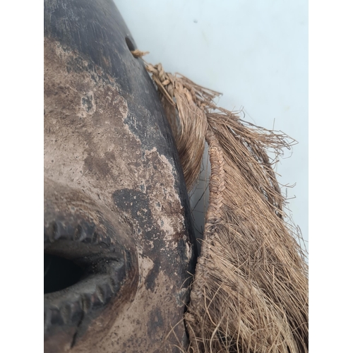 90 - An Ivory Coast Mask with fibre fringe surrounding face with remnants of white polychrome and pierced... 