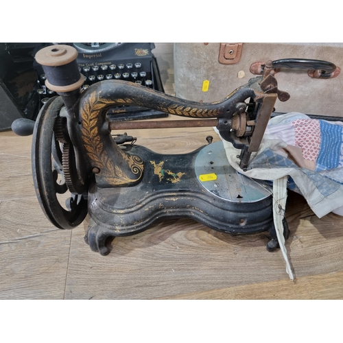 516 - A cast iron black painted Sewing Machine, an electric Sewing Machine and a cased Typewriter, (R6)