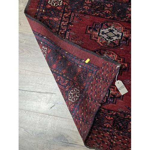 527 - A bordered Persian Rug with three rows of medallions on a red ground, 5ft 7in x 2ft 10in (R3/4)