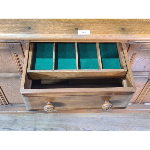 549 - An Ercol elm Dresser with detachable rack, fitted cutlery drawer above three more drawers, flanked b... 