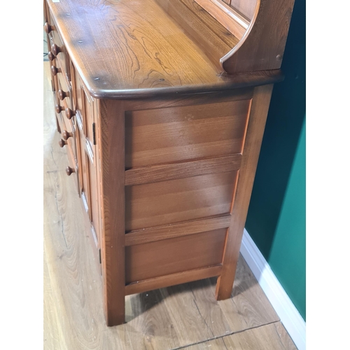 549 - An Ercol elm Dresser with detachable rack, fitted cutlery drawer above three more drawers, flanked b... 