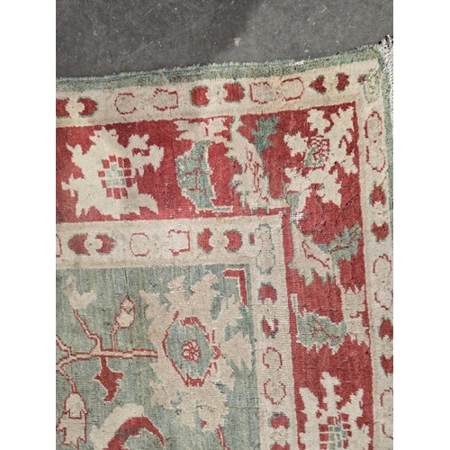 624 - A Turkish style green and red ground Carpet with multiple borders and stylized palmettes, 8ft 6