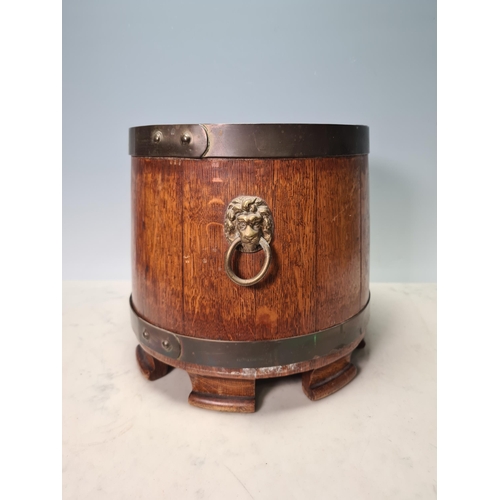 75 - A brass bound oak circular Pot with lion mask and ring handles, 10in diam