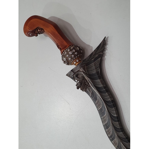 99 - An Indonesian Ceremonial Kris with dragon and striated blade, the grip with diamante set pommel, the... 