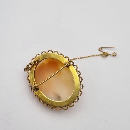 256 - A carved shell Cameo Brooch in a frame of simulated pearls surrounded by gold metal twisted wire fra... 