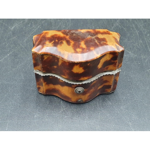 143 - A 19th Century tortoiseshell small Box with serpentine front, containing two small white metal lidde... 