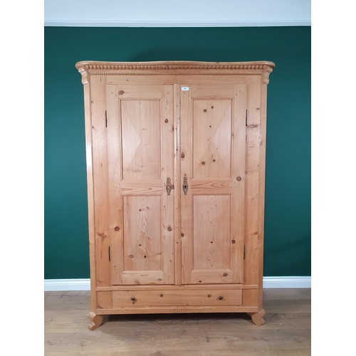 645 - A Continental pine Wardrobe with beaded cornice above pair of panelled doors, the interior fitted wi... 