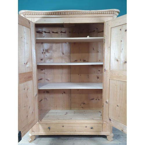 645 - A Continental pine Wardrobe with beaded cornice above pair of panelled doors, the interior fitted wi... 