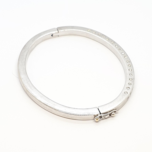 182 - A Diamond hinged Bangle in 18ct white gold the front set brilliant-cut stones, total weight approx 2... 