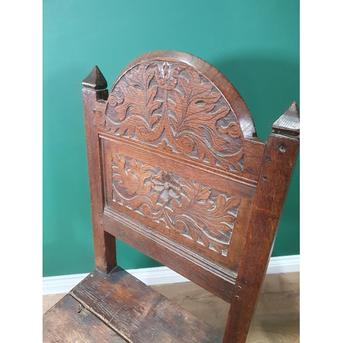 398 - A 17th Century oak Hall Chair with arched leafage carved panel back raised on ball and square cut fr... 