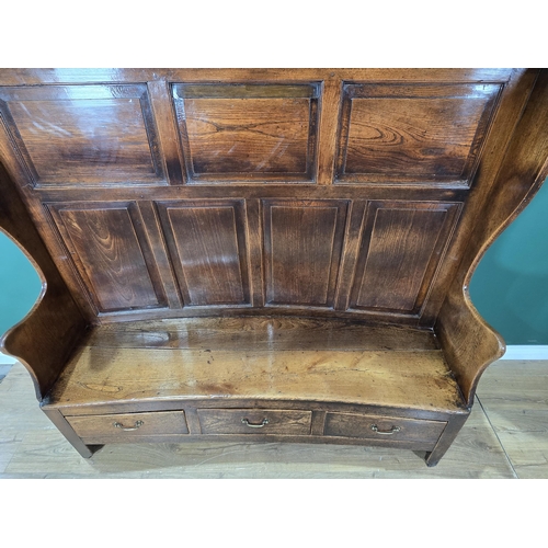 469 - An 18th Century carved oak Wingback Settle with seven fielded panels to the back and the base, fitte... 