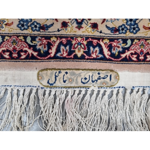 652 - A bordered Persian Rug with floral design in red and blue on a camel ground, signed and having tasse... 