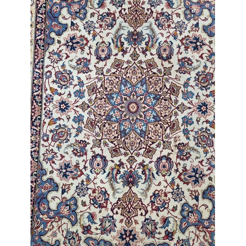 652 - A bordered Persian Rug with floral design in red and blue on a camel ground, signed and having tasse... 