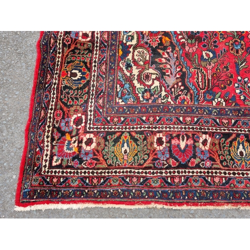 655 - A large Persian woollen Carpet with central cream diamond shaped flower head within red ground with ... 